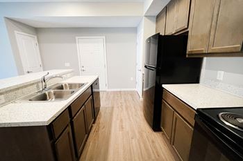 an empty kitchen with wood flooring and wooden cabinets